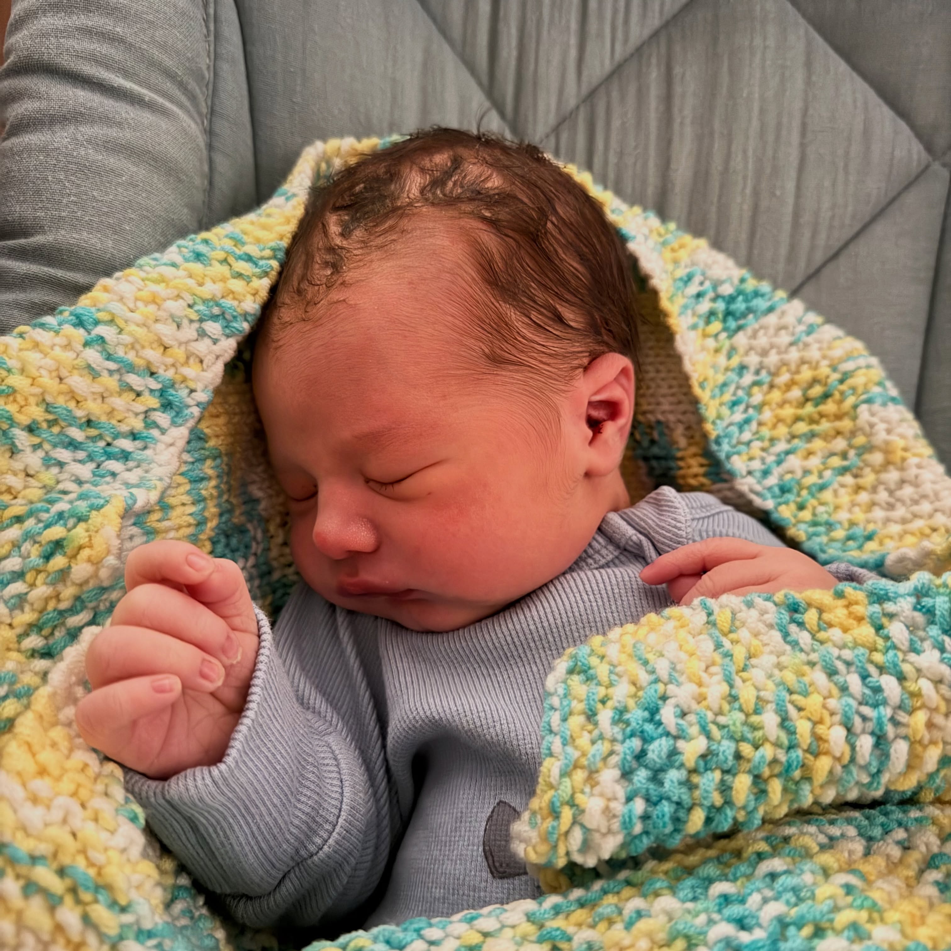 Louis asleep in a knitted blanket